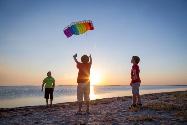 Niños lanzando la cometa arco iris juntos — Foto de Stock