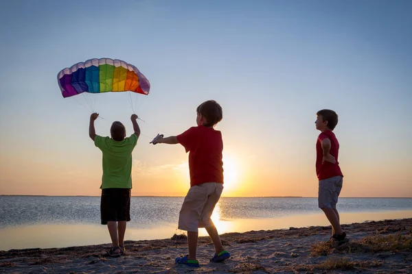 Dzieci razem uruchomienie latawca rainbow — Zdjęcie stockowe