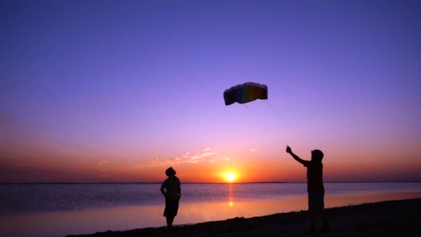 Niños lanzando la cometa arco iris together. cámara lenta — Vídeos de Stock