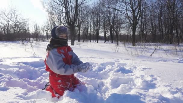 Забавный ребенок играет со снежками в зимнем парке — стоковое видео