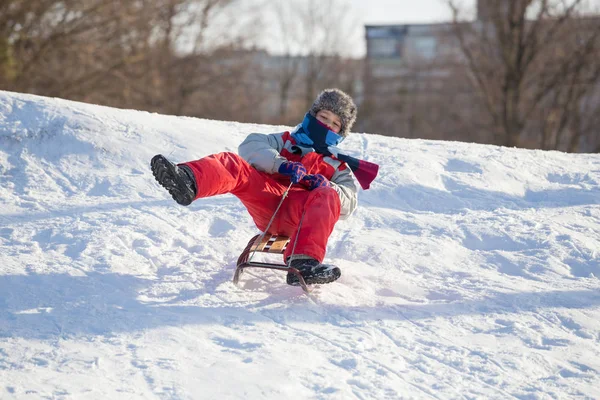 Happy boy riding at the slide on snowy hill — Stock Photo, Image