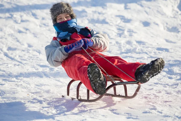 スライドで雪に覆われた丘の上に乗って幸せな少年 — ストック写真