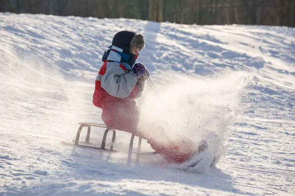スライドで雪に覆われた丘の上に乗って幸せな少年 — ストック写真