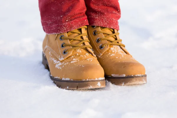 青少年腿在黄色靴子在雪 — 图库照片