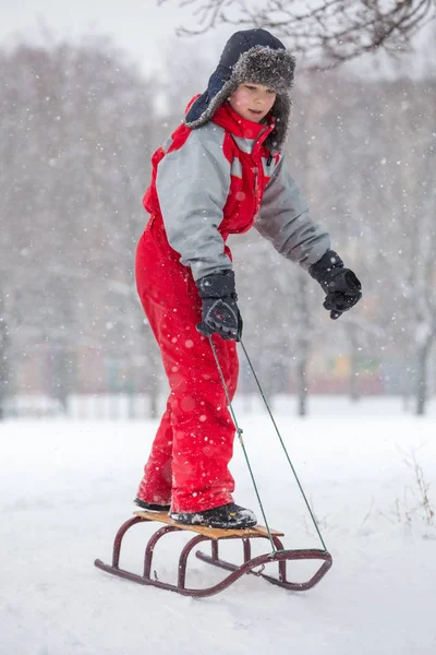 雪に覆われた丘の上のスライドで立っている少年 — ストック写真