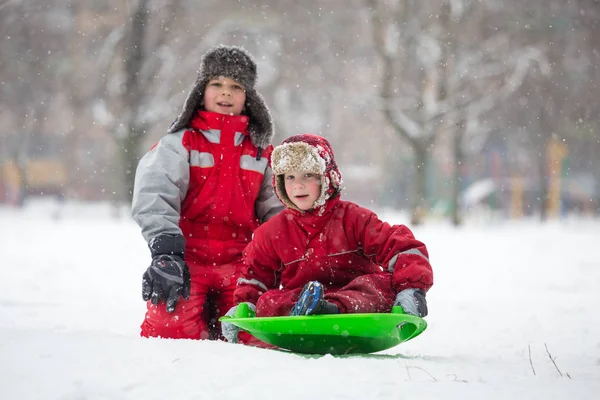 Two boys riding at the slide on snowy park — Stock Photo, Image