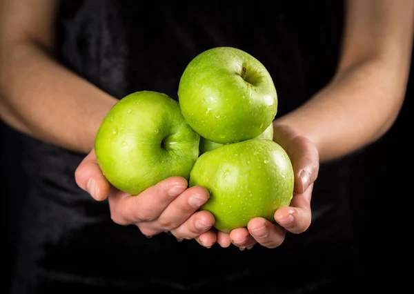 Зеленые яблоки в руках женщины на черном фоне — стоковое фото