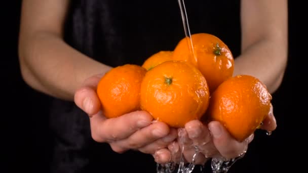 女性の手、スローモーションでオレンジ色のみかんを洗浄 — ストック動画
