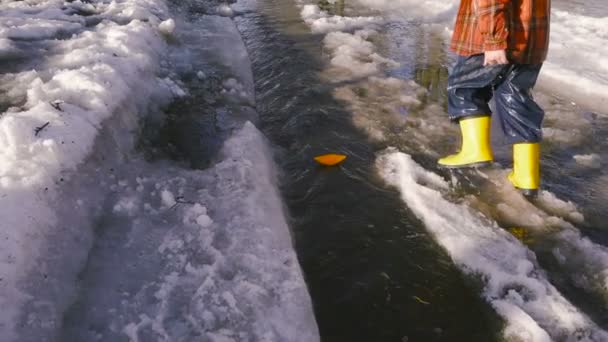 Menino lança um barco de papel no riacho da primavera — Vídeo de Stock