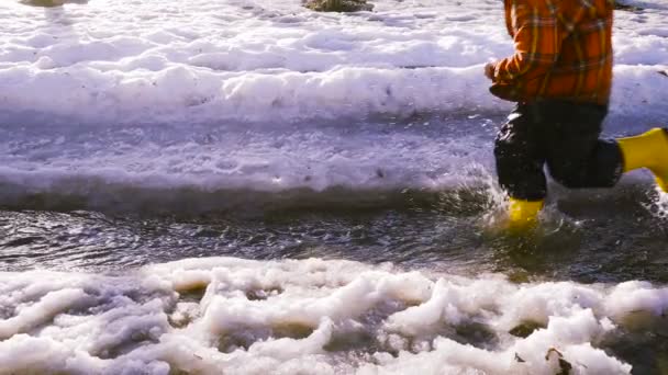 Kind op de kreek van de lente met smeltend ijs — Stockvideo
