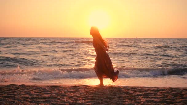 Menina bonita pulando na costa do mar ao nascer do sol — Vídeo de Stock