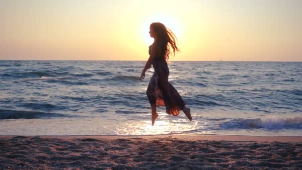 Hermosa chica saltando en la costa del mar al amanecer — Vídeos de Stock