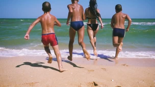 Τέσσερα παιδιά που τρέχουν στη θάλασσα από την παραλία — Αρχείο Βίντεο