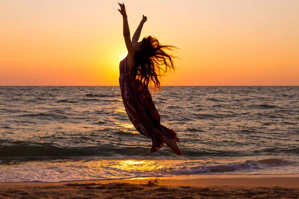 Девушка прыгает на берегу моря с восходом солнца — стоковое фото