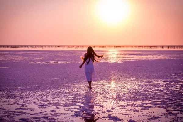 Hermosa joven caminando en el lago de sal al atardecer — Foto de Stock