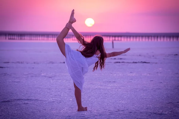 Silueta de chica haciendo ejercicios en el lago de sal al atardecer —  Fotos de Stock