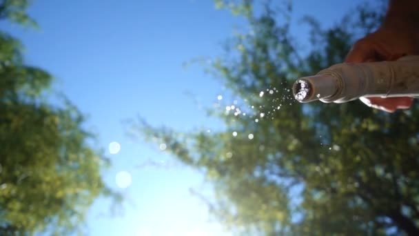 Fallendes Wasser aus dem Wasserhahn gegen blauen Himmel — Stockvideo