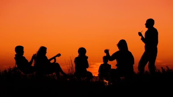 Persone sedute sulla spiaggia con falò al tramonto — Video Stock