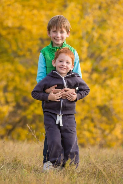 Two kids standing together on autumn landscape — Stock Photo, Image