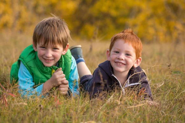 Two kids lying down on autumn landscape — Stock Photo, Image