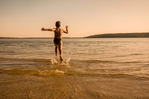 Jongen wordt uitgevoerd op het water met spatten — Stockfoto