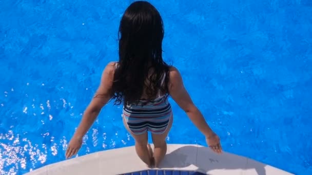 Chica saltando a la piscina azul, cámara lenta, vista aérea — Vídeos de Stock