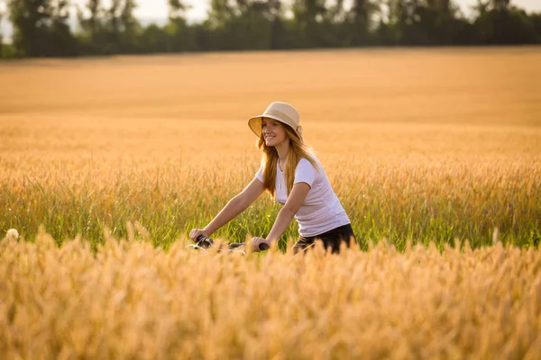 Girl riding on bike at golden wheat field — Stock Photo, Image