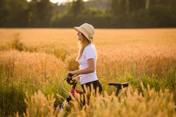 Fille avec vélo au champ de blé doré — Photo