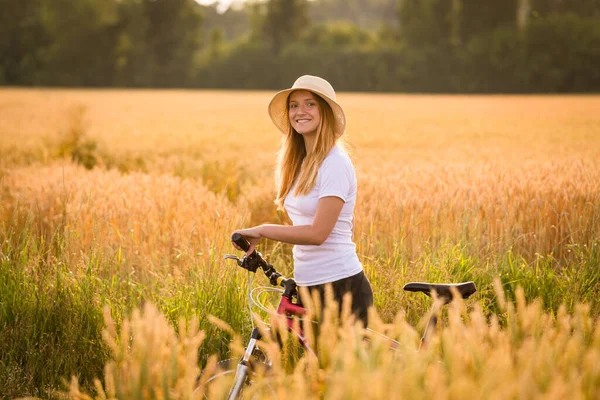 Ragazza con bici a campo di grano dorato — Foto Stock