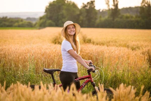 Κορίτσι με ποδήλατο σε χρυσό χωράφι με σιτάρι — Φωτογραφία Αρχείου
