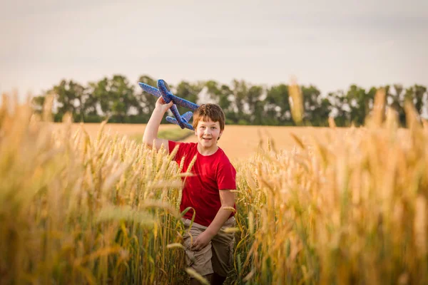 Junge läuft mit Spielzeugflugzeug auf Weizenfeld — Stockfoto