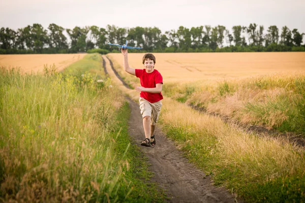 Garçon courir avec jouet avion sur champ de blé — Photo