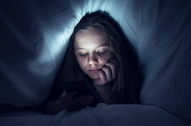 Genç kız yatakta bir telefon kullanma