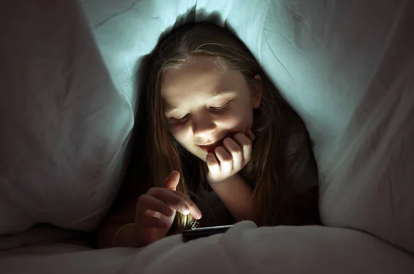 ベッドで携帯電話を使用して若い女の子 — ストック写真