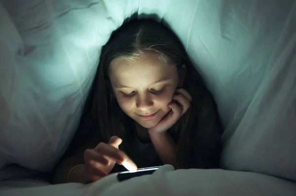 ベッドで携帯電話を使用して若い女の子 — ストック写真