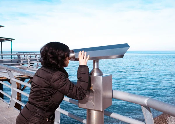 Kvinna som tittar i kikaren på havet däck — Stockfoto