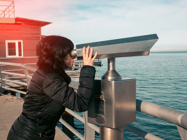 Woman looking in binoculars on the sea deck — Stock Photo, Image
