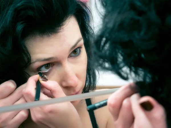Mujer aplicando maquillaje delante del espejo — Foto de Stock