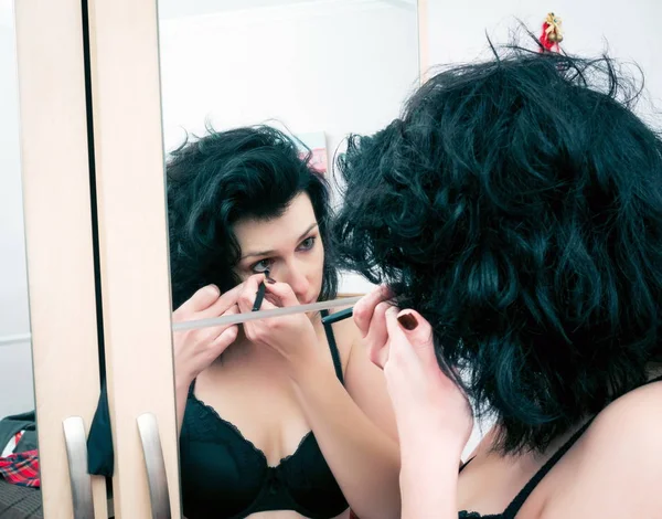 Mulher aplicando maquiagem na frente do espelho — Fotografia de Stock