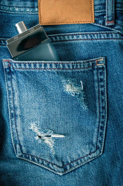 Бутылка духов на джинсах — стоковое фото