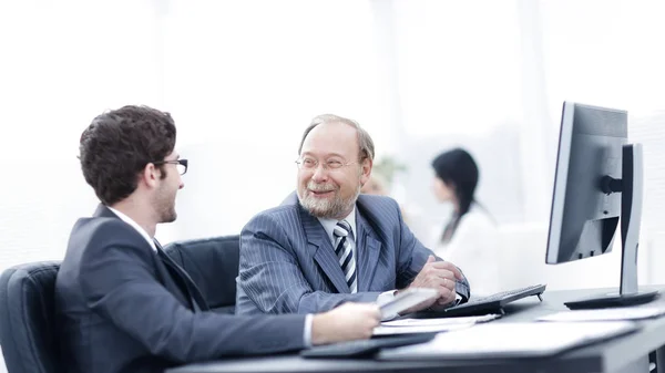 Dos hombres de negocios discutiendo temas de trabajo sentados en su escritorio — Foto de Stock