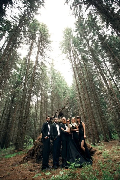 couple and their friends near the hut in a pine forest.