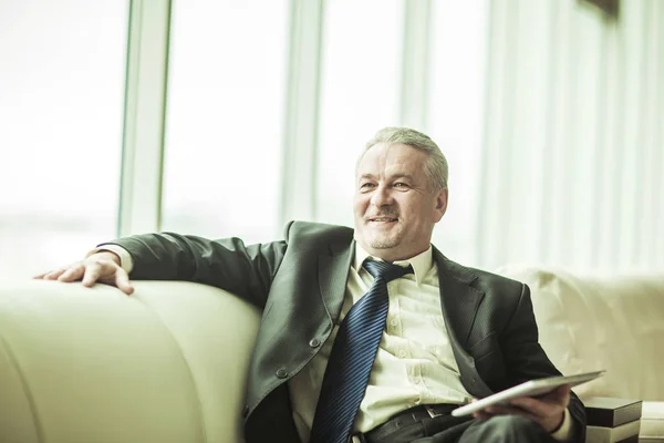 Experienced lawyer with digital tablet sitting on the sofa in the private office — Stock Photo, Image