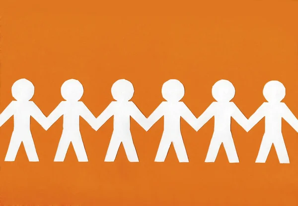 White paper men on a bright orange background. — Stock Photo, Image