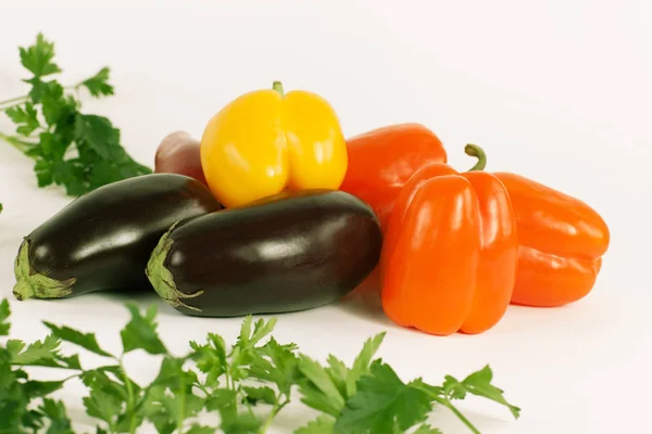 Bell pepper,eggplants and sprigs of parsley on a white background. — Stock Photo, Image