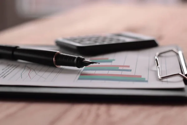 クローズ アップ。金ひっくり返されたペンとテーブルの上の財務グラフ — ストック写真