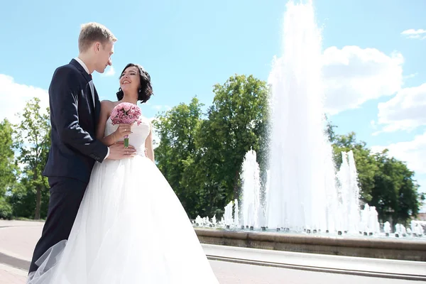 Bruden och brudgummen embracing på en bakgrund av staden. — Stockfoto