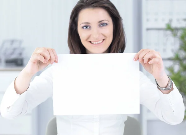Mujer de negocios mostrando hoja en blanco, sentado detrás de un escritorio —  Fotos de Stock