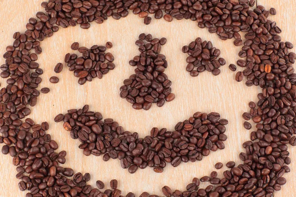 Faccia divertente di chicchi di caffè nero su sfondo di legno — Foto Stock