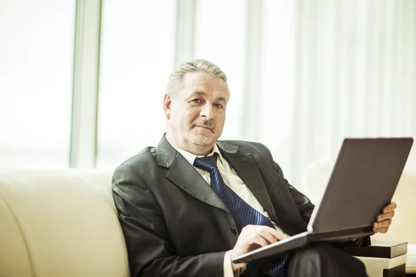 Erfahrener Geschäftsmann am Laptop sitzend auf dem Sofa in einem privaten Büro — Stockfoto